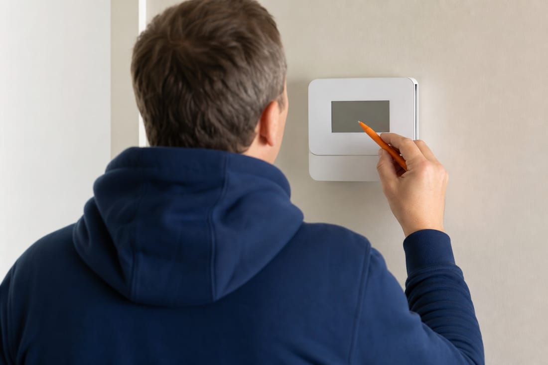 Beispiel: Heizungsmonteur programmiert ein Thermostat, von hinten